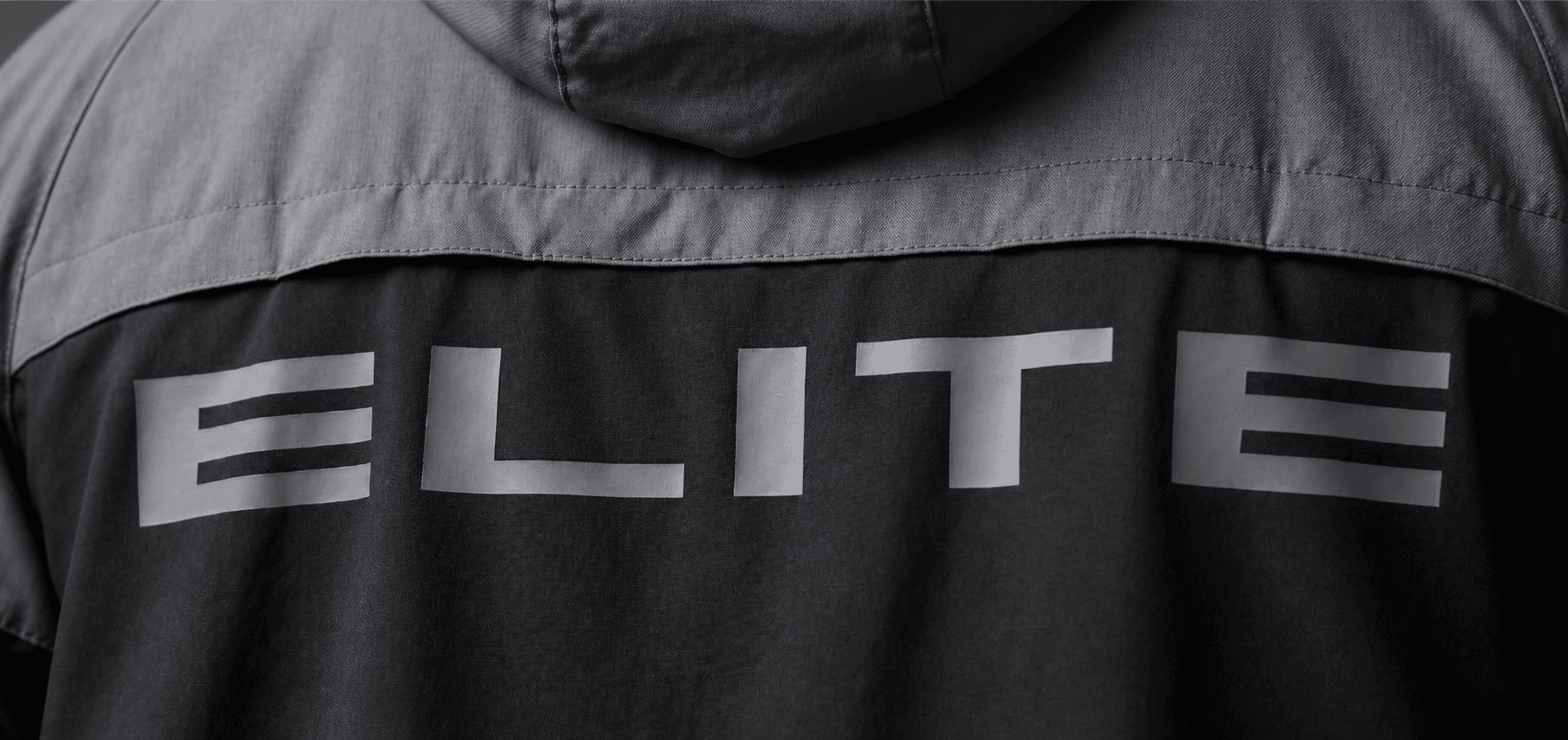 Close-up of the ELITE wordmark across a charcoal performance jacket